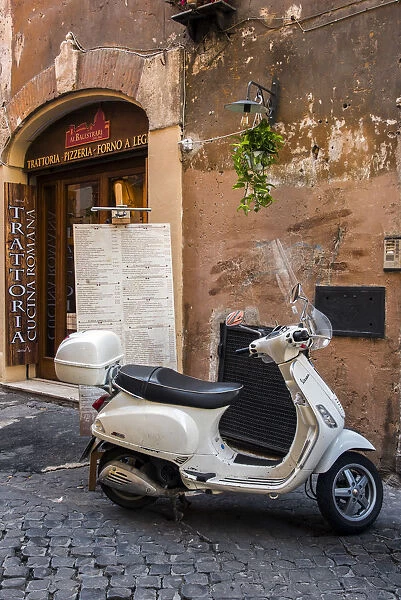 Italian Vespa scooter parked outside a trattoria restaurant in a cobblestone street