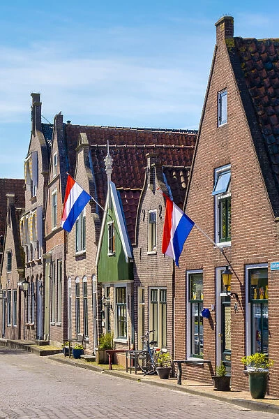 Netherlands, North Holland, Edam. Brick houses with Dutch flags hanging outside for