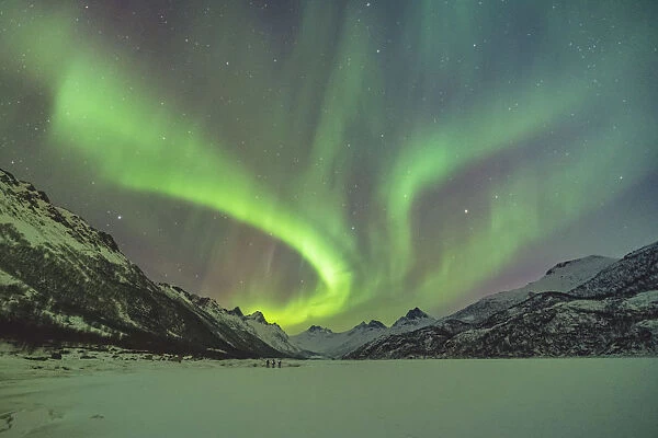 Northern lights with mountains and three people in winter. Kleppstad, Nordland county