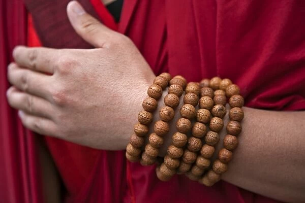 Prayer beads wrapped round the wrist of a red-robed monk