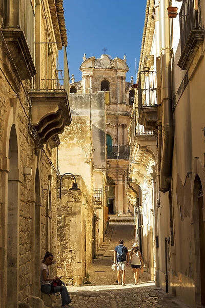 Scicli, Sicily. People walking in the narrow streets with San Giovanni Evangelista