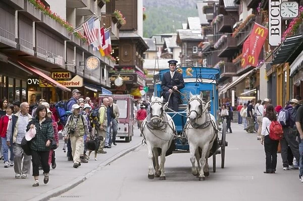 A coach and horses in Zermatt main street Switzerland