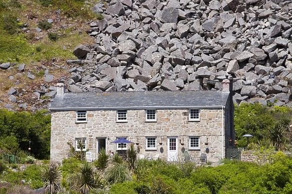 A house at Lamorna cove in Cornwall, UK overshadowed by boulders from an old quarry