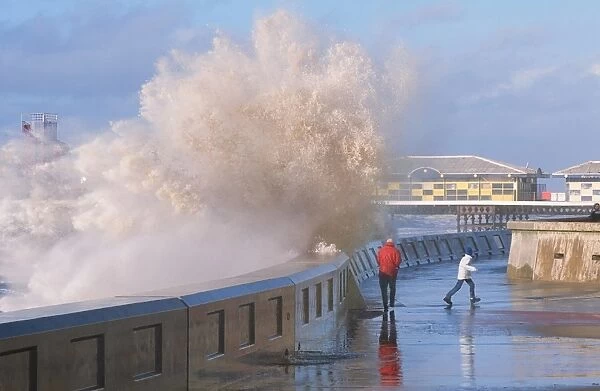 People dodging storm waves breaking over the sea wall at Blackpool Lancashire UK