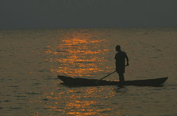 10095708. TANZANIA Lake Tanganyika Mokoro canoe raft paddler on water at sunset