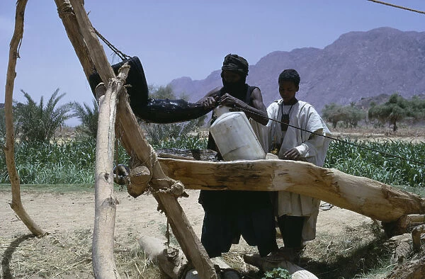 20075116. NIGER Air Mountains Tuareg filling water bottles for agricultural use. toureg