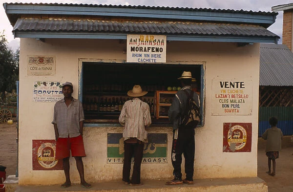 20079305. MADAGASCAR Ihosy Men standing at a kiosk which sells rum and beer