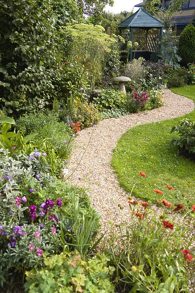 English cottage garden, winding shingle path leading to a gazebo between grass lawn
