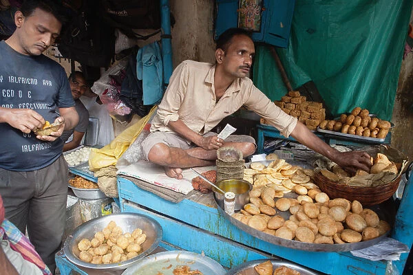 India, West Bengal, Kolkata, A vendor selling snack food including samosas, kachori, and pani puri