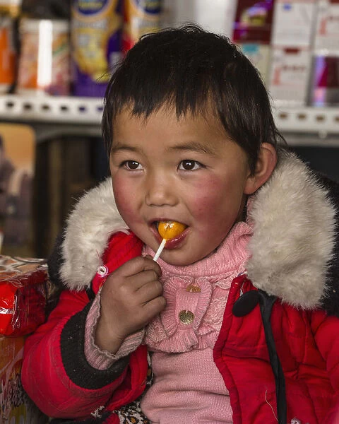A young Tibetan child enjoys a piece of candy in Lhasa, Tibet