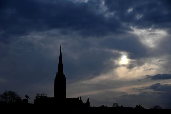 The afternoon sun pierces clouds behind Salisbury Cathedral