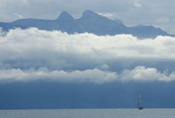 A boat sails on the Leman Lake in front of the misty Ai and Mayen mountains near Lausanne