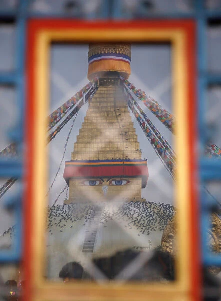 Boudhanath Stupa is reflected in the window of a monastery during Vesak Day in Kathmandu