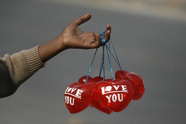 A boy holds Valentines Day balloons for sale along the roadside in Lahore