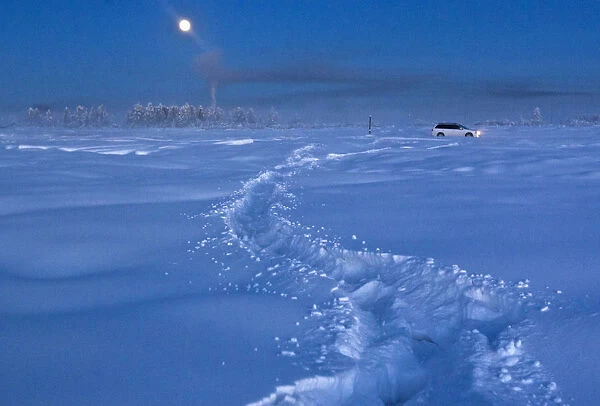 A car drives through the snow at night near Vostochnaya meteorological station