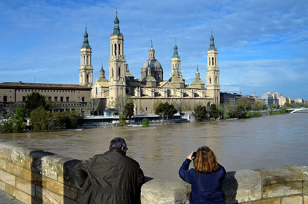 A couple observes the River Ebro close to overflowing, following heavy rains