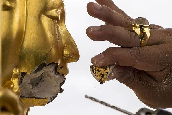 A craftsman fixes the statue of Hindu god Brahma after it was damaged during the deadly