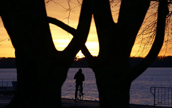 A cyclist looks at sunset from the shore of lake Tegel in Berlins Reinickendorf district
