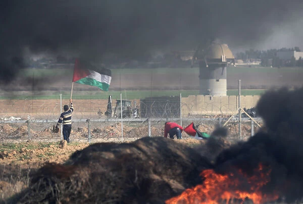 Demonstrator holds a Palestinian flag during clashes with Israeli troops near the border