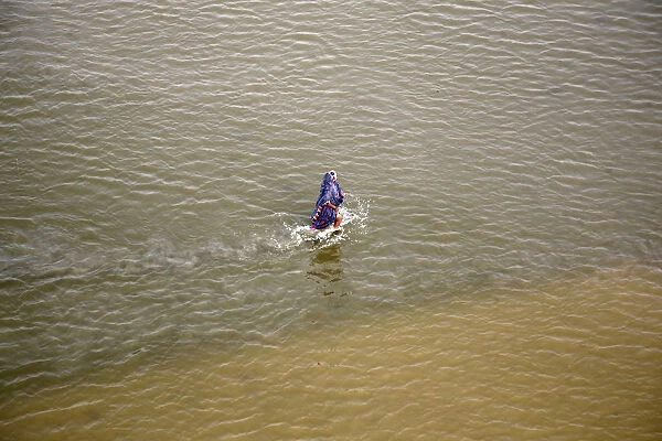 A devotee walks back to shore after taking a dip in the waters of the river Ganges in the