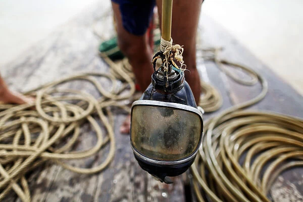 A diver holds his mask on a small boat on Yangon River after searching for coal