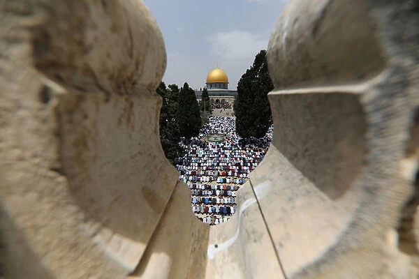 The Dome of the Rock is seen in the background as Palestinians pray on the second Friday