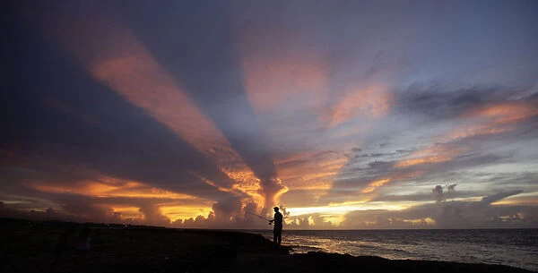 A fisherman casts his line as the sun sets on the outskirts of Havana