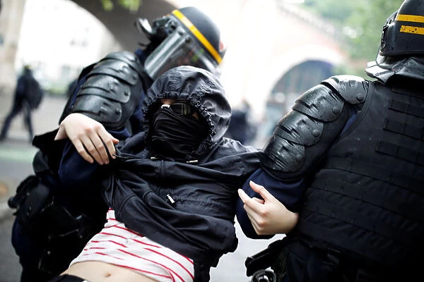 French riot police apprehend a masked and hooded protester after clashes at a