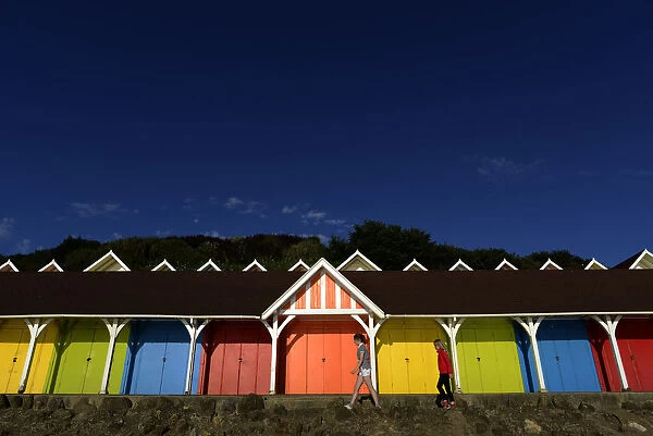 Two girls walk past beach huts in the North Bay in Scarborough
