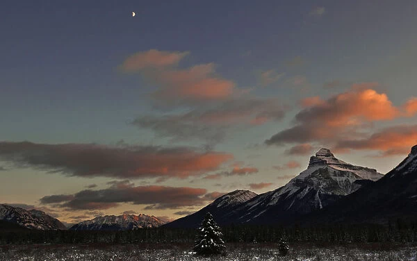 A half moon sits over Moose Meadow at sunset in Banff National Park near Lake Louise