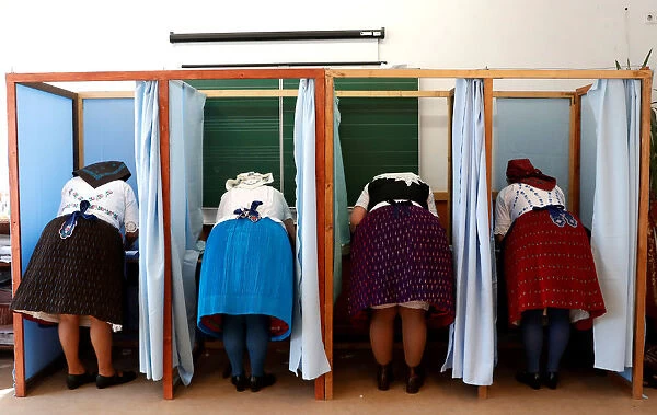 Hungarian women, wearing traditional costumes, fill their ballot papers at a polling