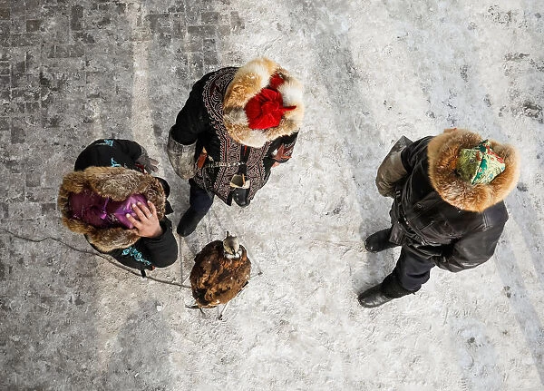 Hunters stay next to a tamed golden eagle during an annual competition at Almaty