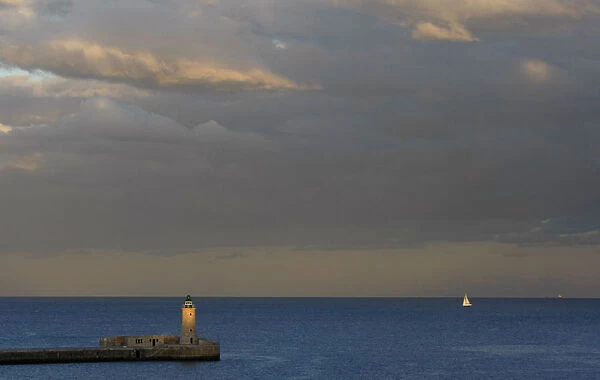 A lighthouse is seen at dusk in a harbour in Valletta