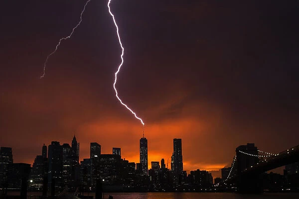 Lightning strikes One World Trade Center in Manhattan as the sun sets behind the city