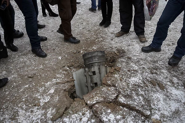 Local residents look at the remains of a rocket shell on a street in the town of