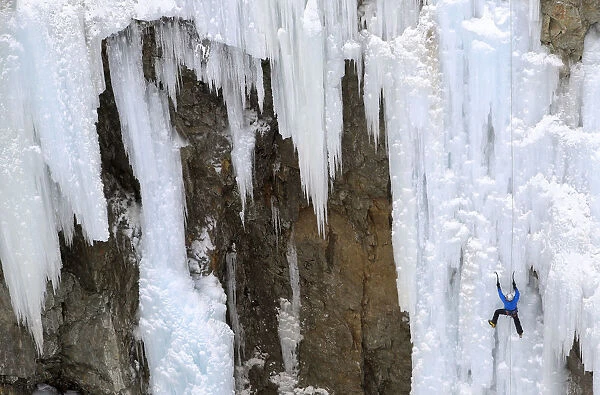 A man climbs up an artificially made wall of ice near the Swiss mountain resort of