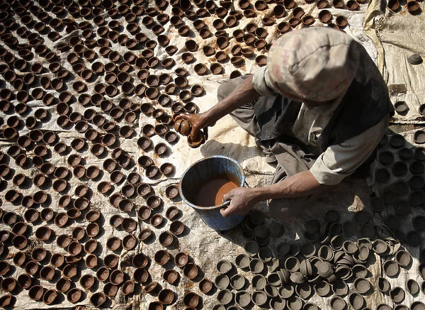 A man dries earthenware oil lamps or Diyo in the sun outside his workshop