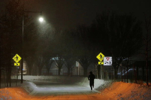 A man jogs on Memorial Drive during winter snow storm Grayson in Cambridge