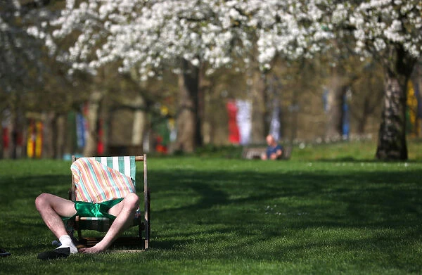 A man relaxes in the sunshine in St James Park in central London
