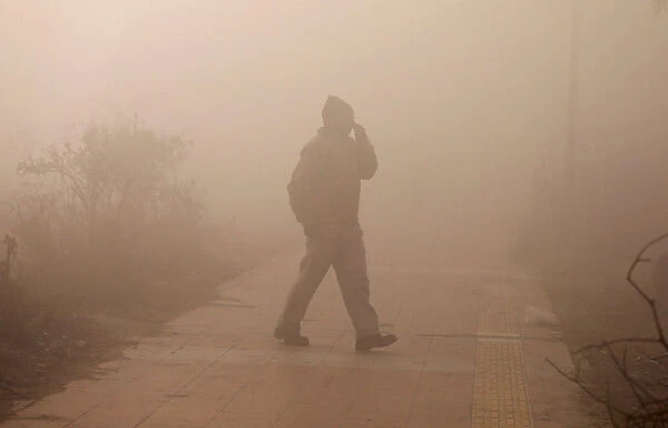 A man walks on a pedestrian path on a foggy winter morning in New Delhi