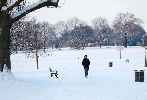 A man walks in a snow covered park in south London