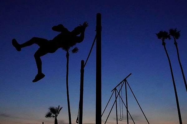 A man works in his high bar skills at sunset in the Venice Beach area of Los Angeles