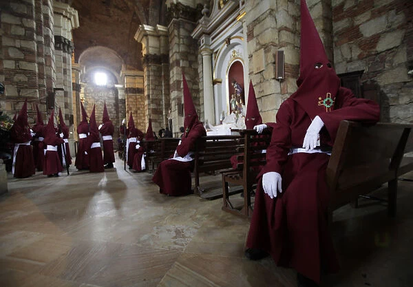 Members of the Nazarenos brotherhood rest inside a church during a Holy Week procession