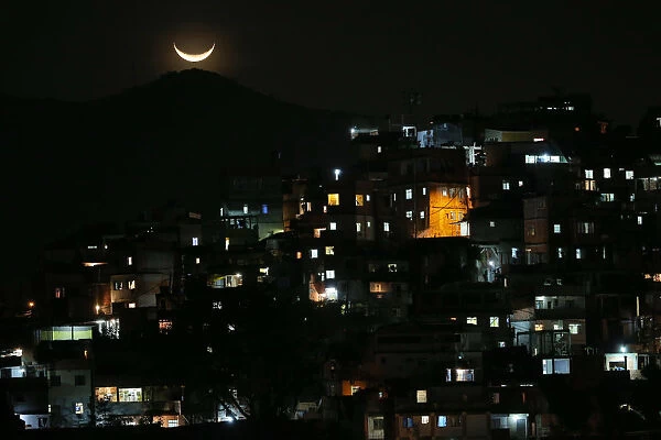 The moon is seen over a slum near Copacabana Beach in Rio de Janeiro, Brazil