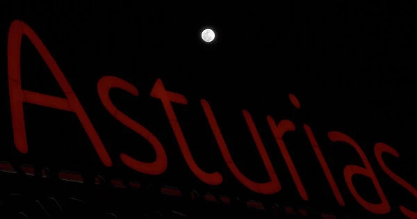 A full moon super moon is seen above a luminous sign with the name of the region
