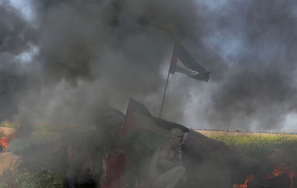Palestinian demonstrators take cover during clashes with Israeli troops
