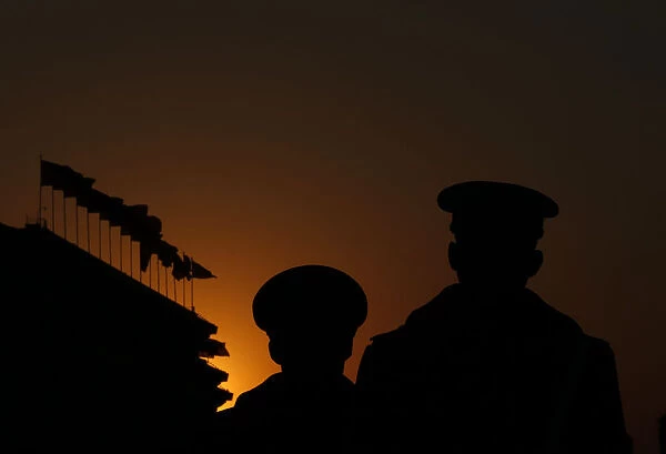 Paramilitary policemen stand guard at Tiananmen Square as the sun sets over the Great