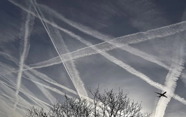 A passenger plane flies through aircraft contrails in the skies near Heathrow Airport in
