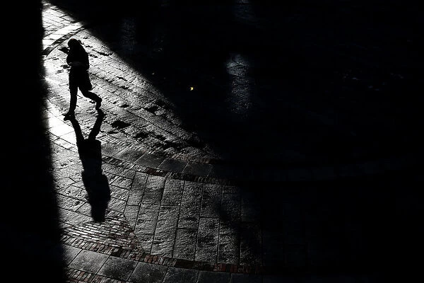 A pedestrian walks through Quincy Market on a warm winter afternoon in downtown in Boston
