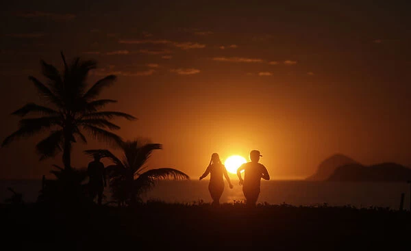 People exercise in Barra da Tijuca beach during the sunrise in Rio de Janeiro